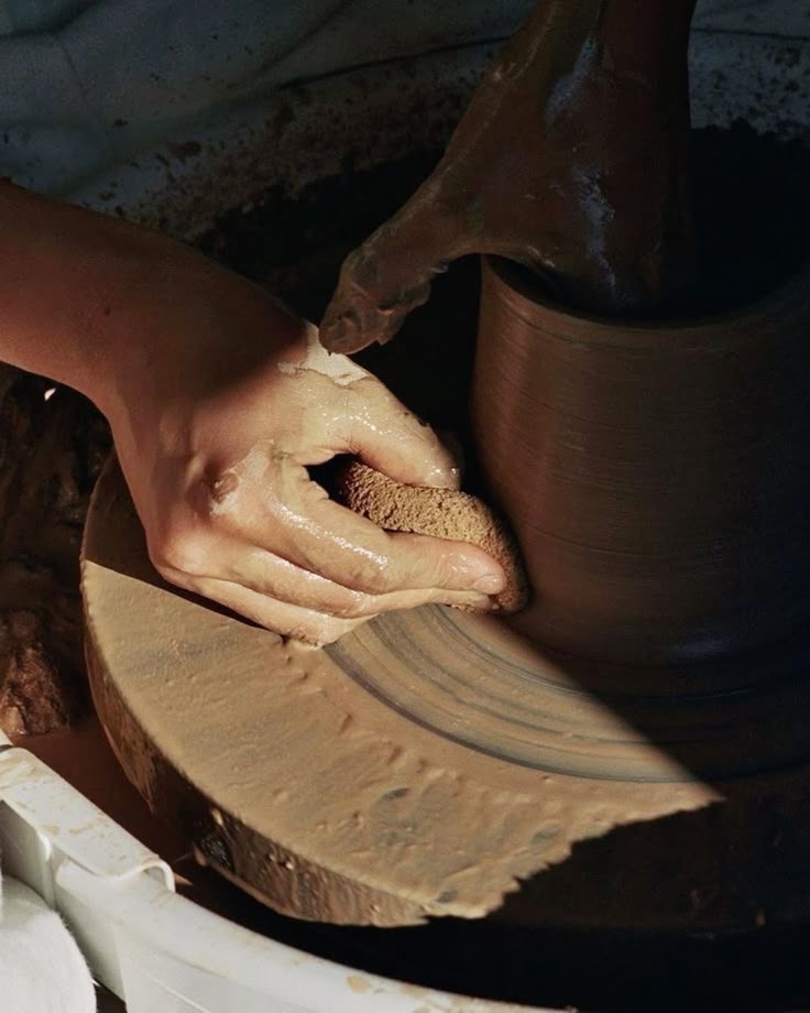 Hands shaping clay on a pottery wheel
